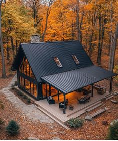 an aerial view of a house in the woods with trees and leaves on the ground