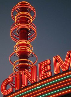 a large neon sign that says cinema on top of a building with lights around it