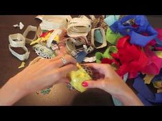 a woman is cutting paper with scissors and other crafting supplies on the table next to her