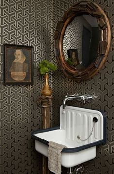 a bathroom sink sitting under a mirror next to a wall mounted faucet with a painting on it