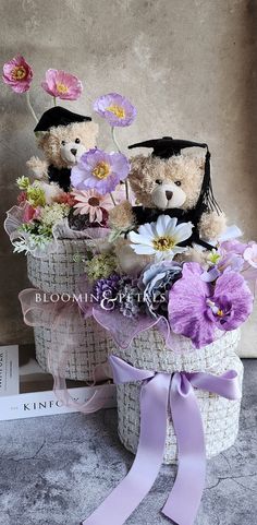 two teddy bears sitting in a basket with flowers