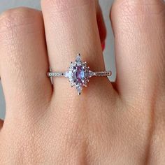 a woman's hand with a ring on it that has an oval shaped pink diamond in the center