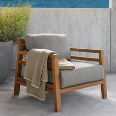 a chair with a blanket on it next to a potted plant and the ocean