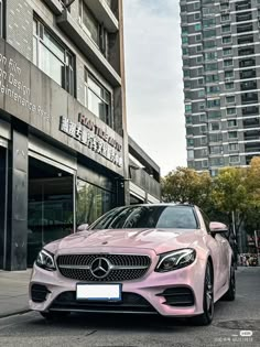 a pink car parked in front of a tall building