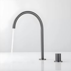 a faucet with water running from it on a white countertop next to a canister