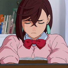 an anime character wearing a pink shirt and red bow tie sitting at a desk in front of a bookshelf