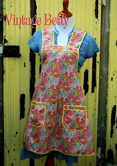 a woman's apron dress is on display in front of a yellow wall with the words vintage betty