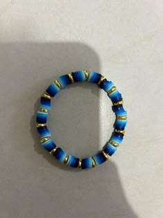 a blue and gold beaded bracelet sitting on top of a white table next to a wall