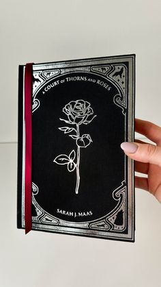 a person holding up a book with a rose on it