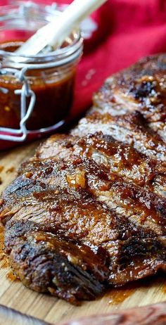 a steak on a cutting board next to a jar of bbq sauce