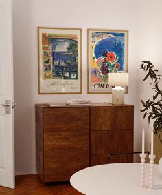 a living room with two paintings on the wall and a white table in front of it