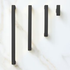 three black handles on a white marble surface