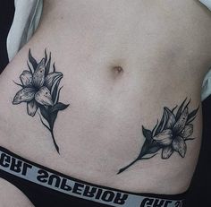 a woman's stomach with two flowers on it and an inscription underneath the tattoo