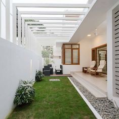 an outdoor living area with grass, rocks and plants on the side of the house