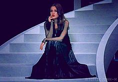 a woman sitting on top of a set of stairs with a microphone in her hand