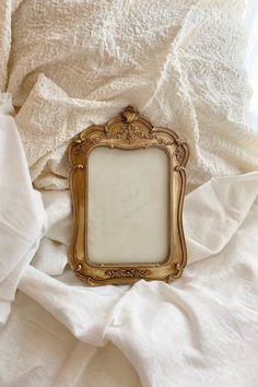 an ornate gold frame sitting on top of white sheets