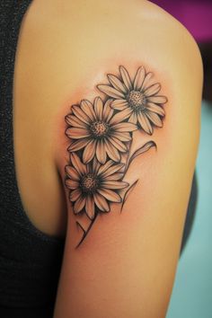 Tattoo of three daisy flowers on upper arm. Daisy Shoulder Tattoos For Women, Daisy Back Tattoo, Rose And Daisy Tattoo, Coneflower Tattoo, Daisy Tattoo Ideas, Yellow Rose Tattoo, Daisy Tattoos, Daisy Tattoo Designs, Yellow Rose Tattoos