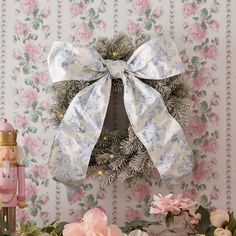 a wreath with a white bow on it next to flowers and a nutcracker