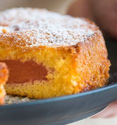 a person holding a plate with a cake on it and powdered sugar on top