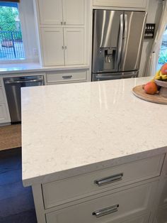 a kitchen with white counter tops and stainless steel appliances