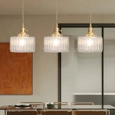 three pendant lights hanging over a dining room table with chairs and tables in front of it