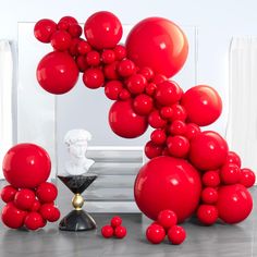 red balloons are floating in the air near a busturine and other items on a table