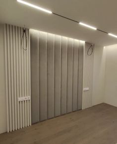 an empty room with wooden floors and vertical blinds on the wall, in front of a radiator