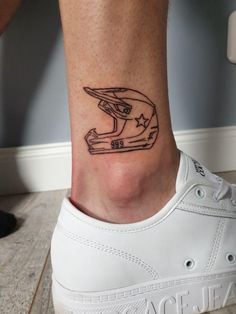 a person's foot with a small helmet tattoo on the left side of their ankle