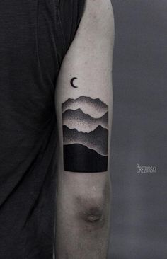 a man with a mountain and moon tattoo on his arm