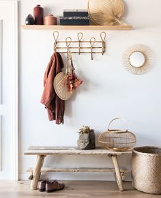 a wooden bench sitting next to a wall with hooks on it's sides and two baskets