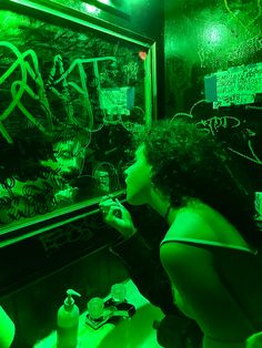 a woman is writing on a blackboard in a dark room with green lights and graffiti