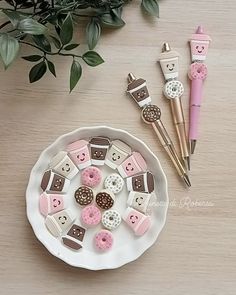 a white plate topped with pink and brown donuts next to cupcakes on top of a table