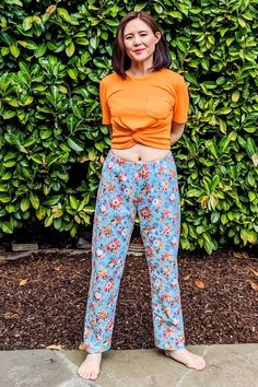 a woman standing in front of a bush with her hands on her hips and smiling at the camera