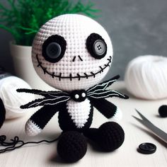 a crocheted jack skellingy doll sitting next to yarn and scissors on a table