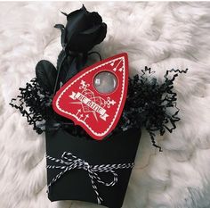 a black box with a red and white triangle shaped decoration on it sitting on a fur surface