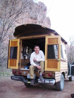 a man is sitting in the back of a truck with his camper attached to it