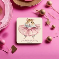 a coaster with a mouse in a pink tutu skirt on it next to cupcakes