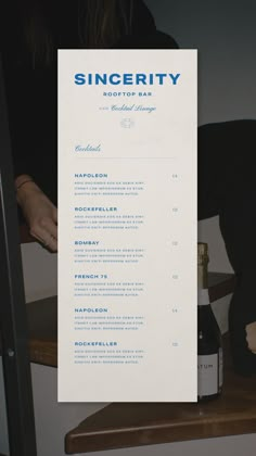 a person sitting at a table with a bottle of wine in front of them and a menu on top of it