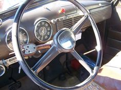 the interior of an old car with steering wheel and gauges