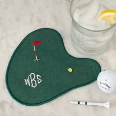 a golf ball and tee on a table with a glass of water next to it