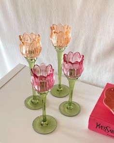 three wine glasses sitting on top of a table next to a pink box and red object