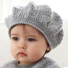 a small child wearing a knitted hat and scarf on top of a white couch