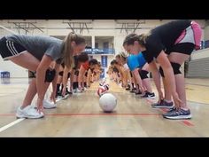 the girls are lined up to kick a soccer ball on the floor in an indoor gym