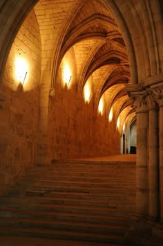 an old building with stone arches and stairs leading up to the second floor, at night