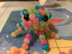 a toy made out of plastic beads sitting on top of a tiled floor next to a table