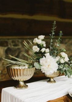 two vases filled with flowers sitting on top of a white tablecloth covered table