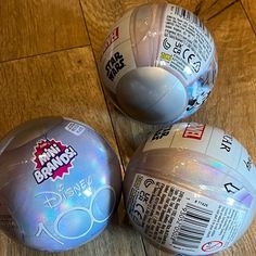 three plastic beach balls sitting on top of a wooden floor next to eachother