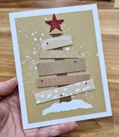 a hand holding up a card with a christmas tree made out of strips of paper