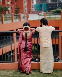 two people standing next to each other near a fence