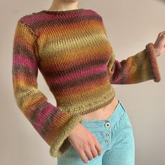 a woman wearing a colorful sweater and blue pants with her hand on her hip, posing for the camera